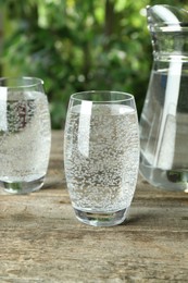 Photo of Soda water in glasses and jug on wooden table