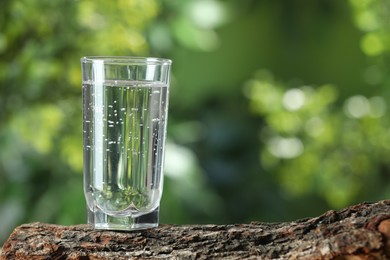 Soda water in glass on wooden surface outdoors, space for text