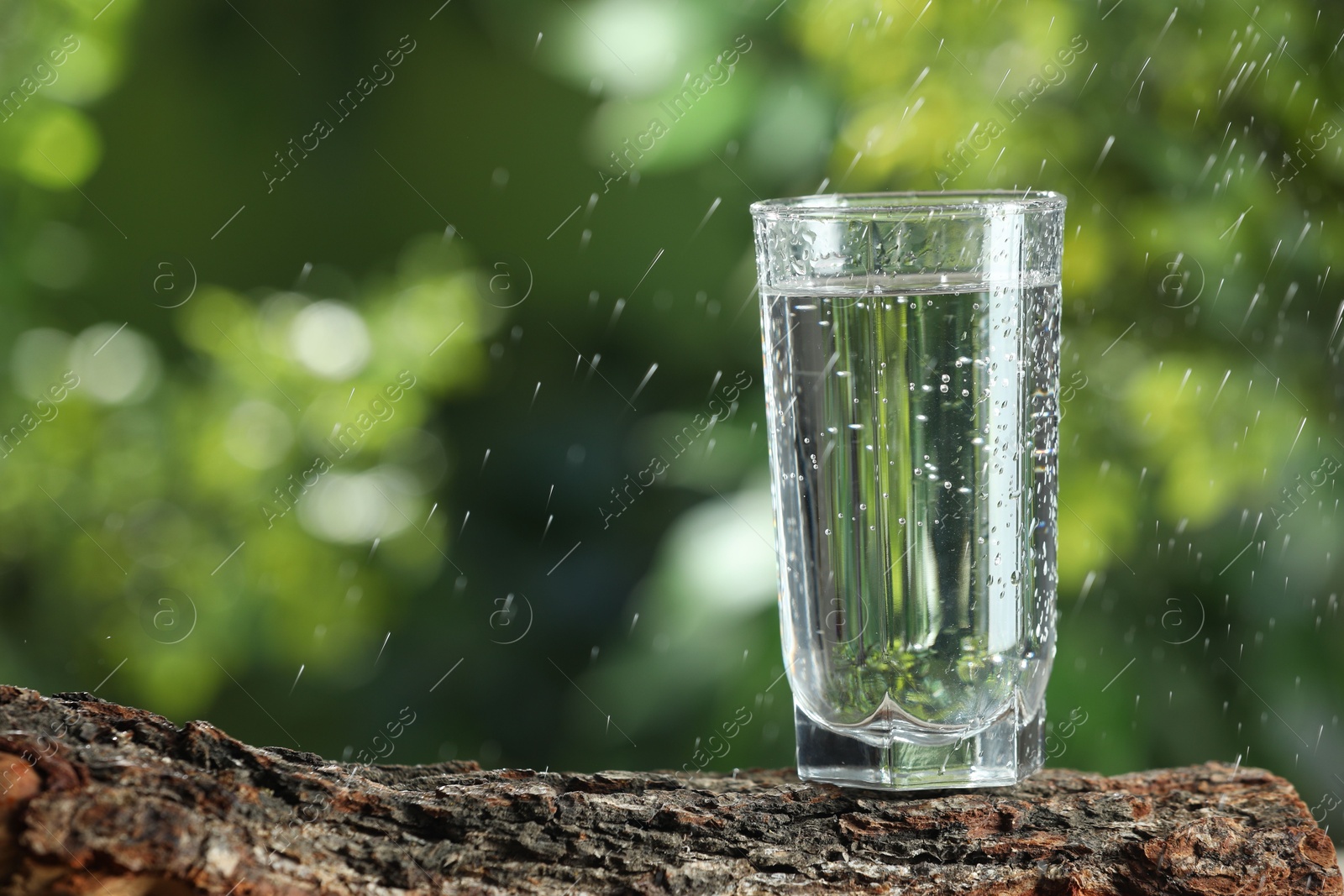 Photo of Soda water in glass on wooden surface under drops outdoors, space for text