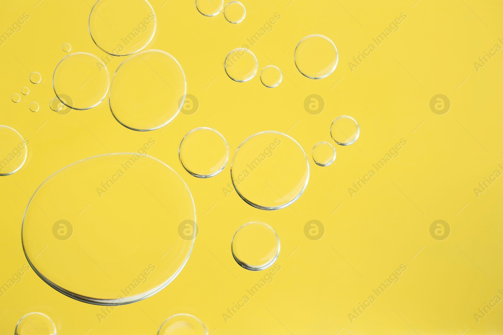 Photo of Sample of cosmetic oil on yellow background, macro view