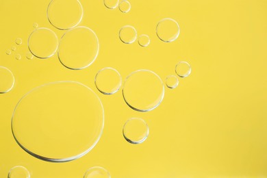 Photo of Sample of cosmetic oil on yellow background, macro view