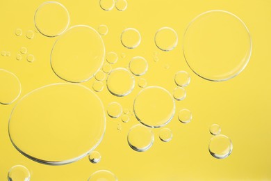 Sample of cosmetic oil on yellow background, macro view