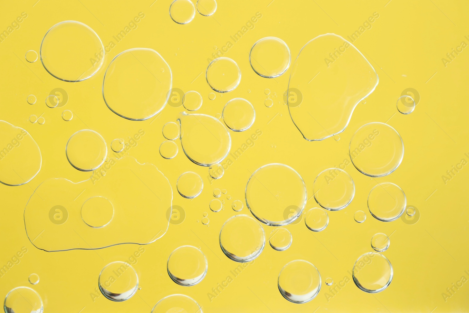 Photo of Sample of cosmetic oil on yellow background, macro view