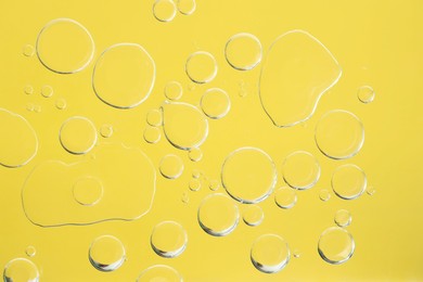 Photo of Sample of cosmetic oil on yellow background, macro view