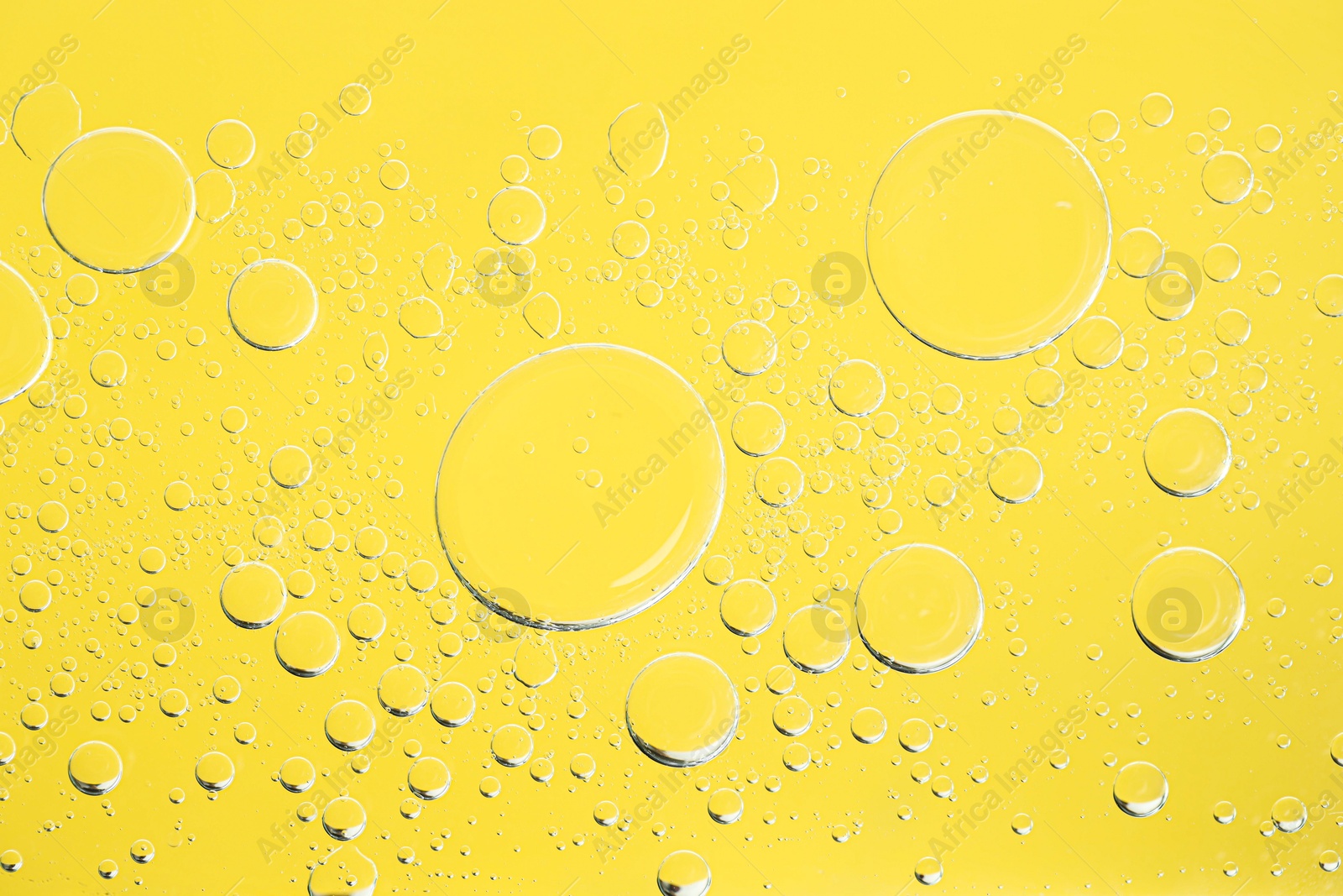 Photo of Sample of cosmetic oil on yellow background, macro view