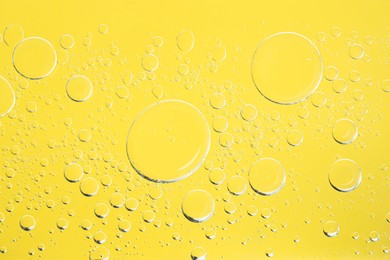 Photo of Sample of cosmetic oil on yellow background, macro view