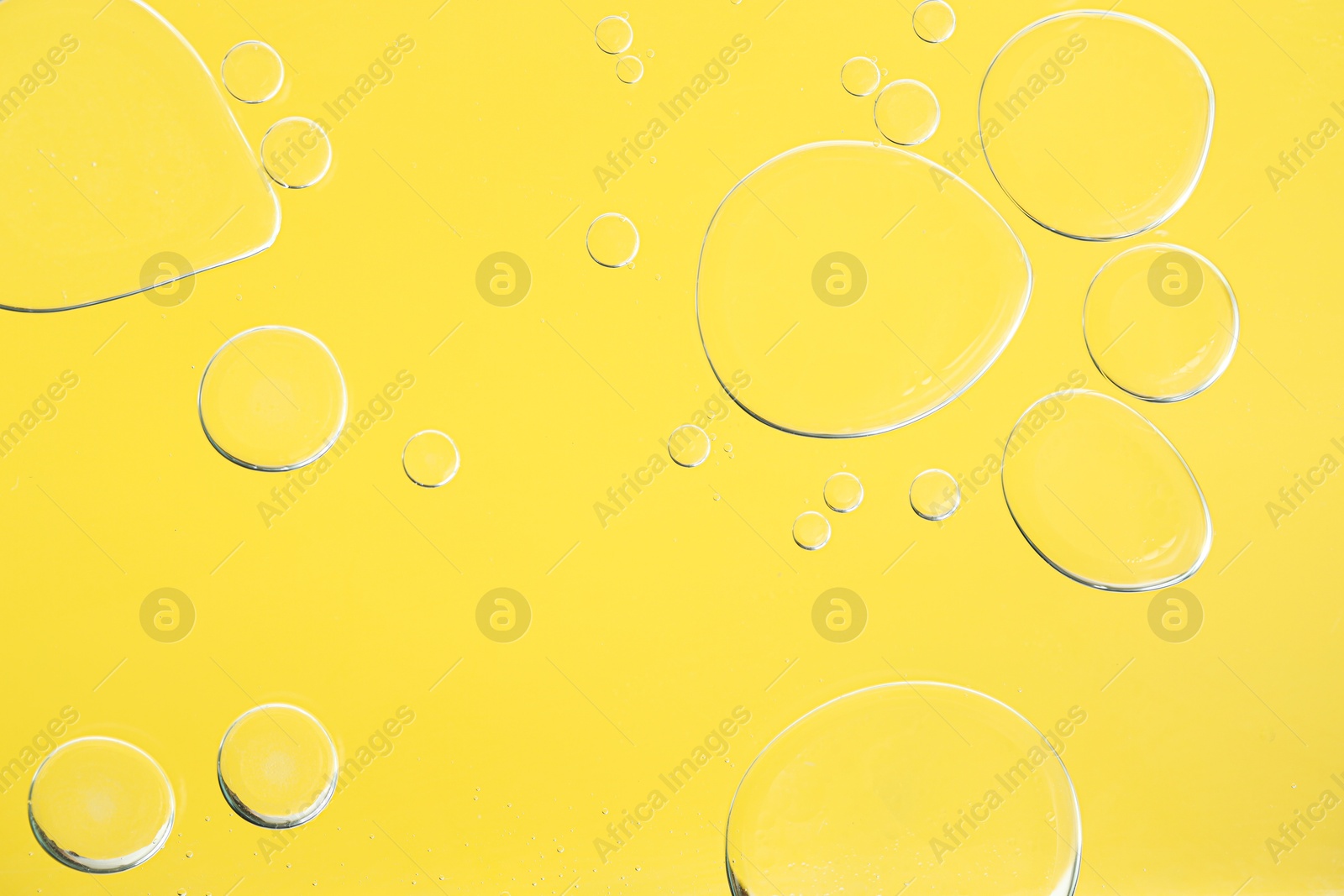 Photo of Sample of cosmetic oil on yellow background, macro view