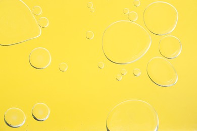 Sample of cosmetic oil on yellow background, macro view