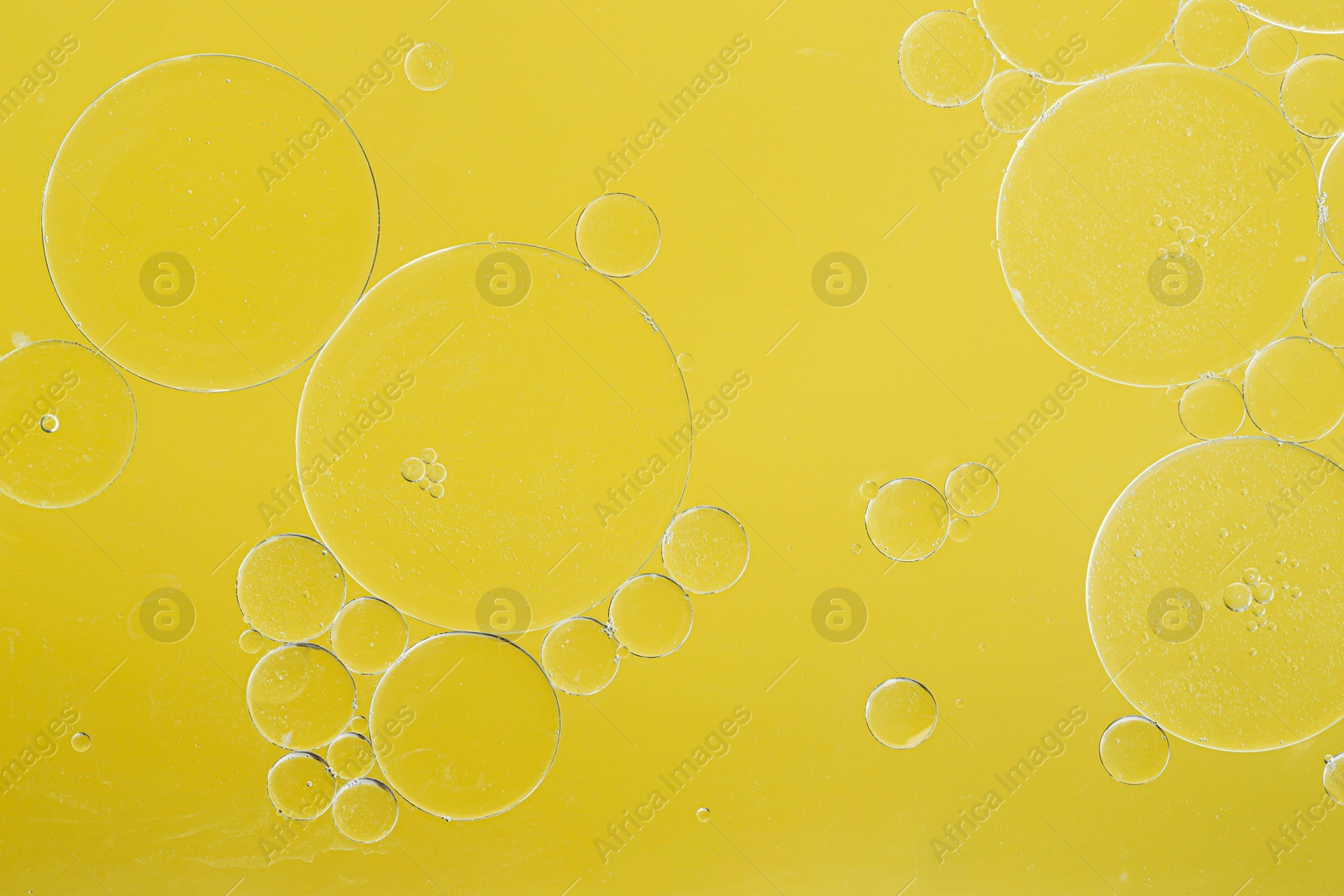 Photo of Sample of cosmetic oil on yellow background, macro view