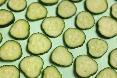 Photo of Slices of fresh cucumbers on turquoise background, above view