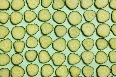 Photo of Slices of fresh cucumbers on turquoise background, flat lay