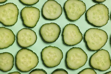 Photo of Slices of fresh cucumbers on turquoise background, flat lay