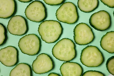 Photo of Slices of fresh cucumbers on turquoise background, flat lay