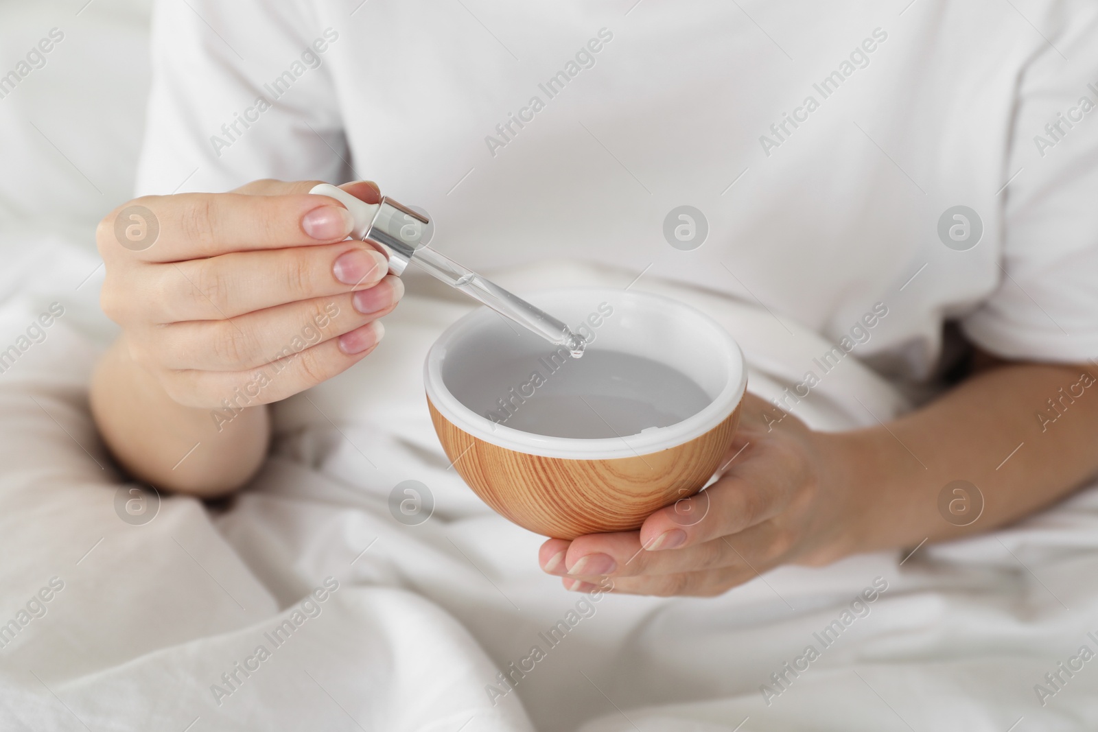 Photo of Woman adding essential oil to aroma diffuser at home, closeup