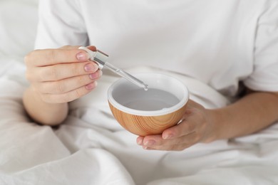 Photo of Woman adding essential oil to aroma diffuser at home, closeup