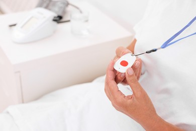 Photo of Senior woman with emergency call button on bed in hospital, closeup