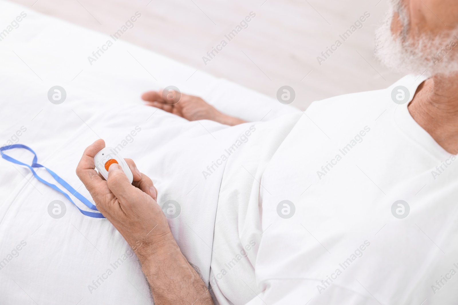 Photo of Senior man pressing emergency call button on bed in hospital, closeup