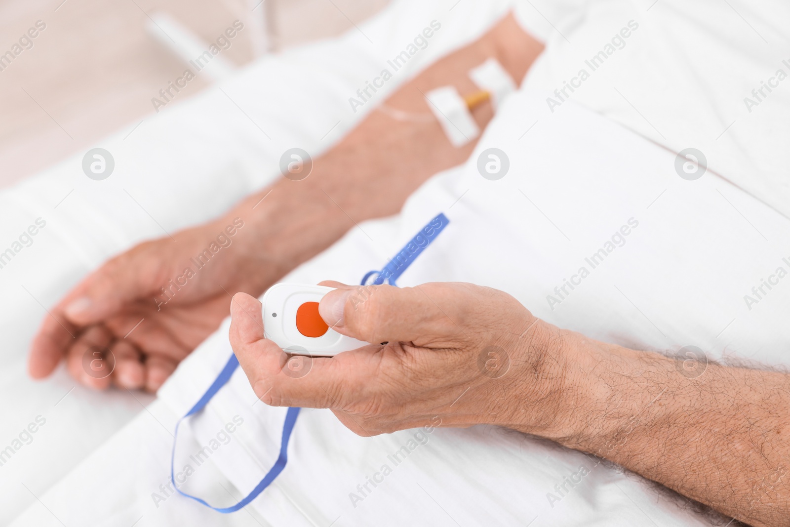 Photo of Senior man pressing emergency call button on bed in hospital, closeup