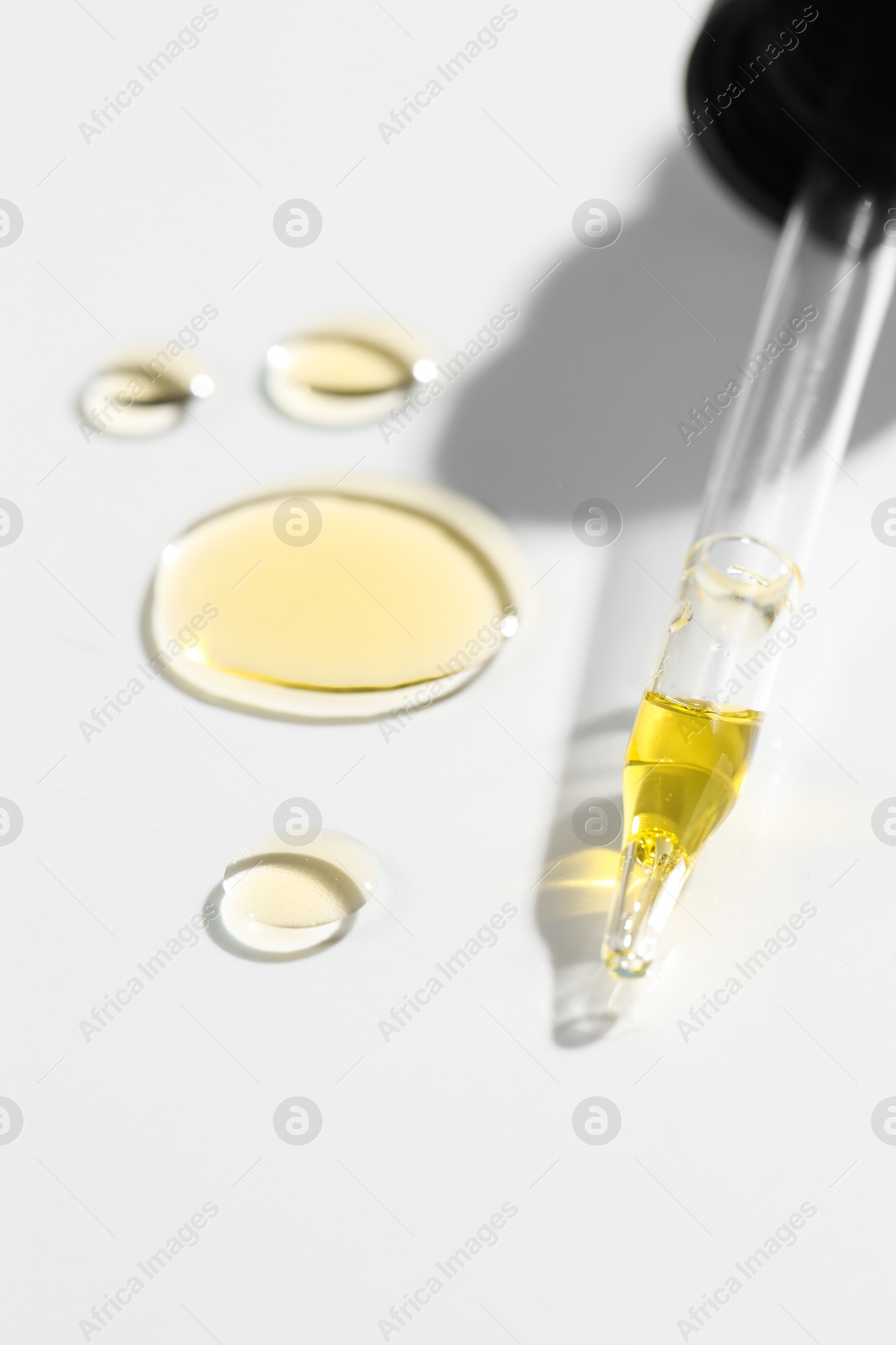 Photo of Cosmetic oil and pipette on light grey background, closeup