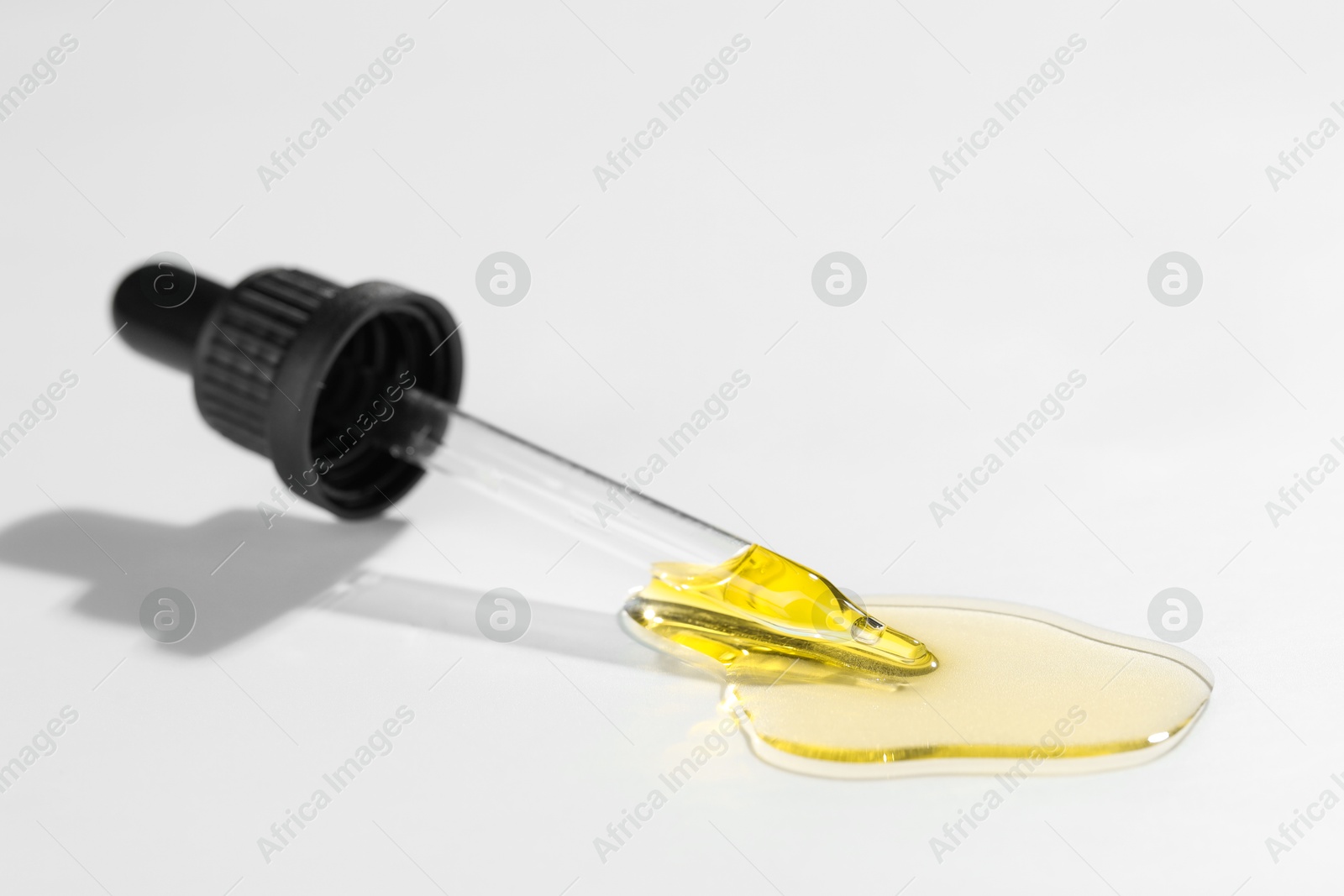 Photo of Cosmetic oil and pipette on light grey background, closeup