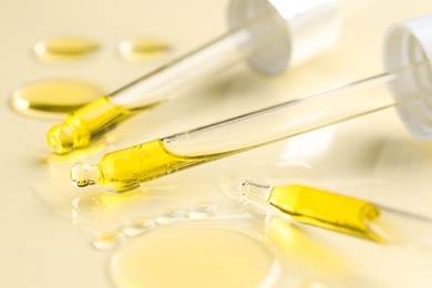 Photo of Cosmetic oil and pipettes on dark beige background, closeup