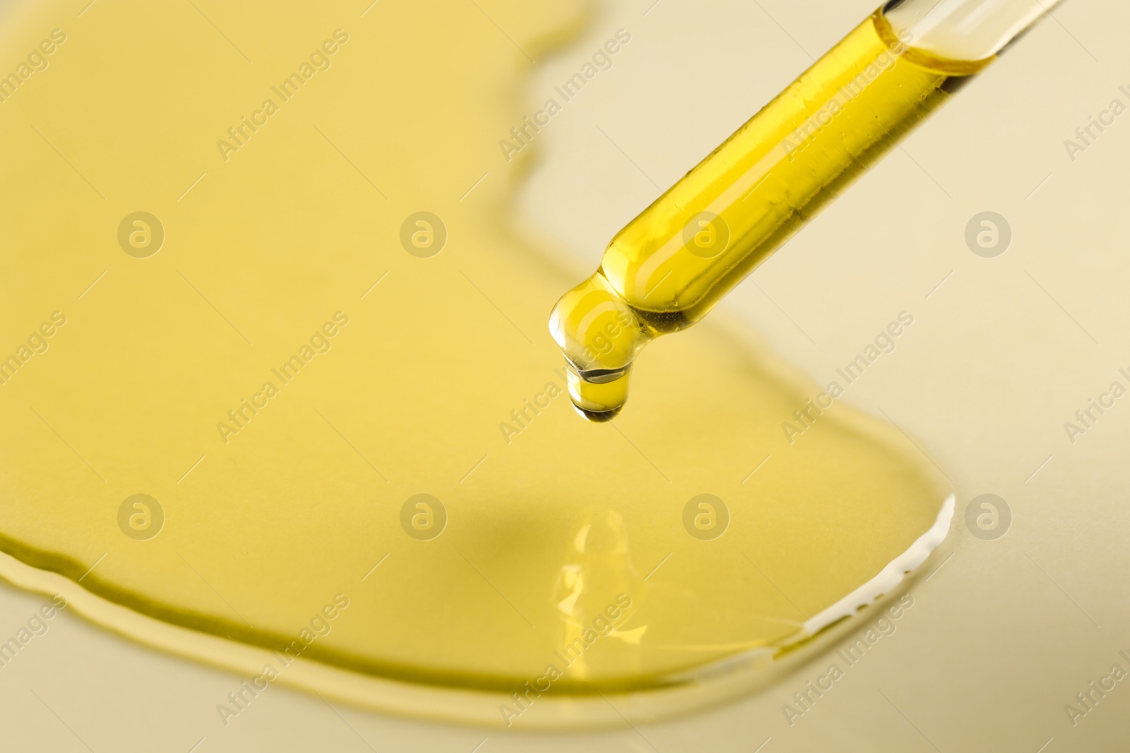 Photo of Cosmetic oil dripping from pipette on dark beige background, closeup. Space for text