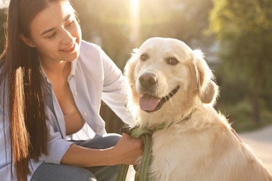 Photo of Happy owner with cute Golden Retriever dog outdoors on sunny day