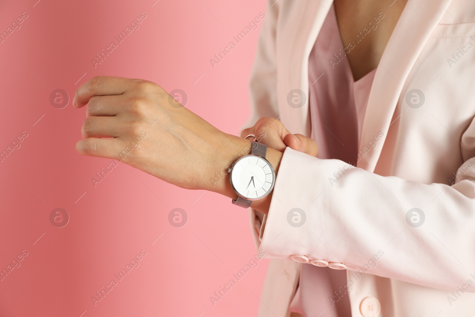 Photo of Beautiful woman in stylish white suit and watch on pink background, closeup