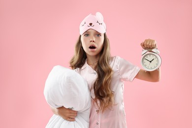 Photo of Overslept girl with sleep mask, pillow and alarm clock on pink background