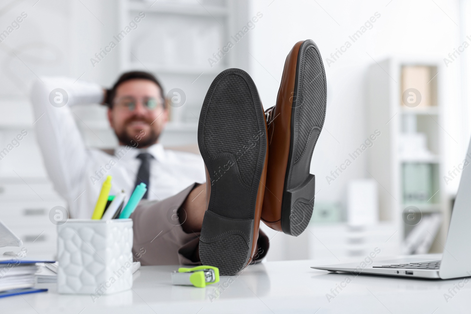 Photo of Businessman holding legs on table in office, selective focus. Break time