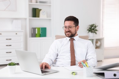 Photo of Smiling businessman working at table in office