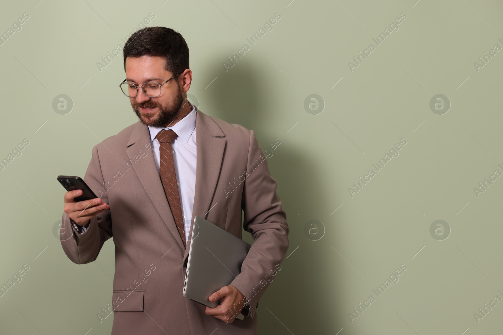 Photo of Smiling businessman with smartphone and laptop on green background. Space for text