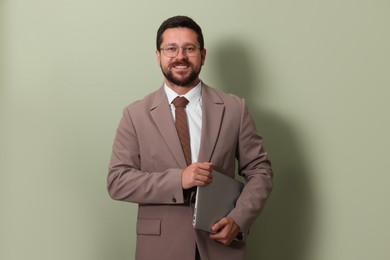 Photo of Smiling businessman with laptop on green background