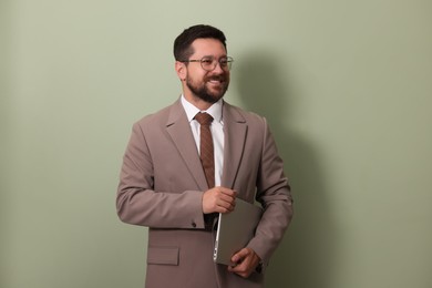 Smiling businessman with laptop on green background