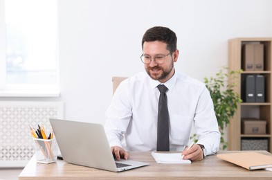 Portrait of smiling businessman working at table in office