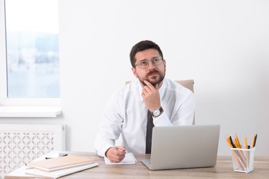 Photo of Portrait of thoughtful businessman at table in office