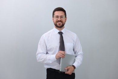 Portrait of smiling businessman with laptop on white background