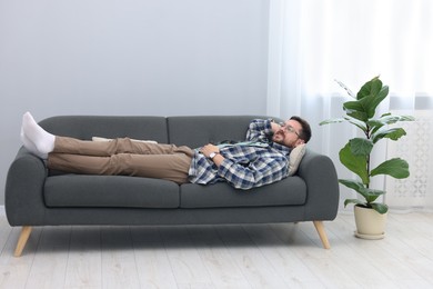 Photo of Smiling man relaxing on sofa at home