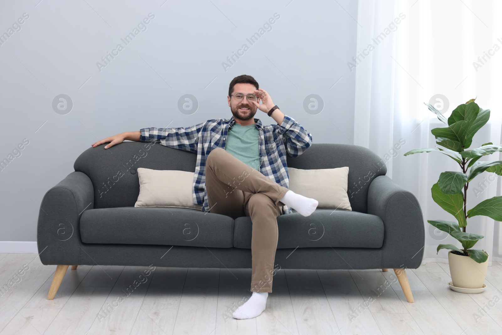 Photo of Smiling man relaxing on sofa at home