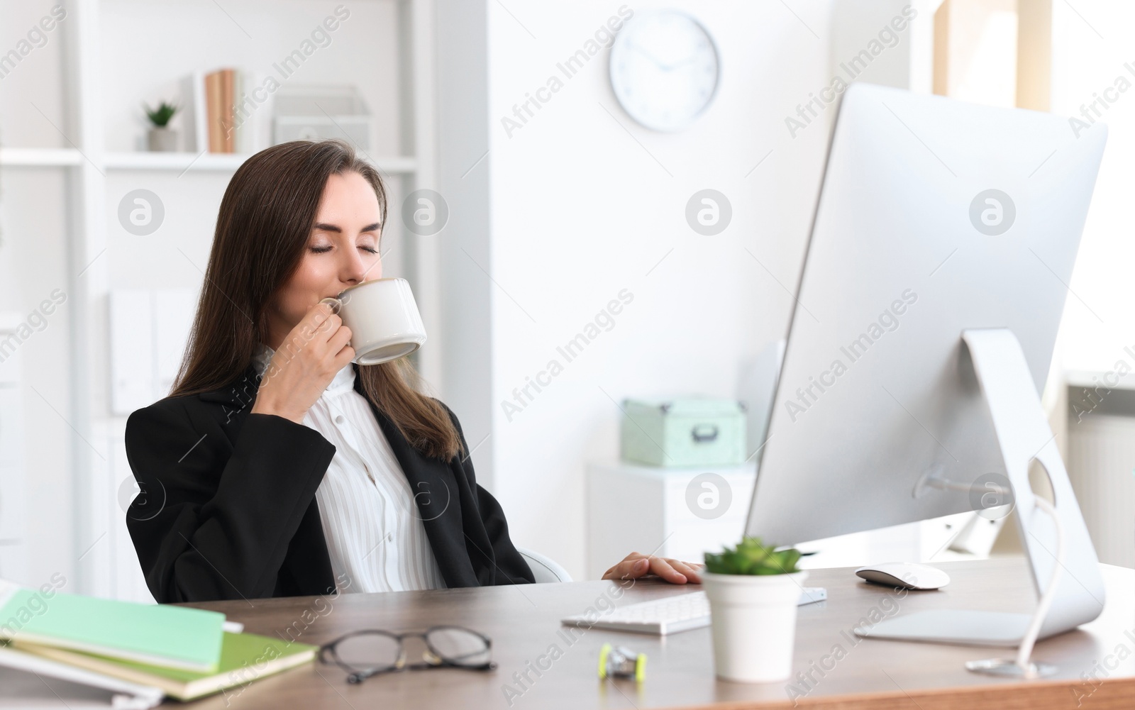 Photo of Businesswoman drinking coffee at table in office. Break time