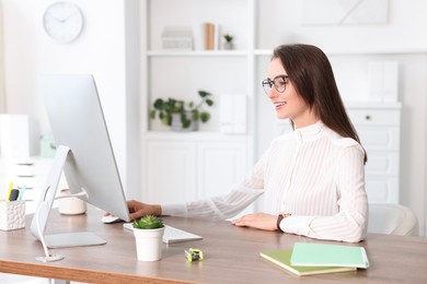 Photo of Smiling businesswoman working at table in office