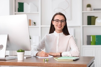 Photo of Portrait of smiling businesswoman at table in office