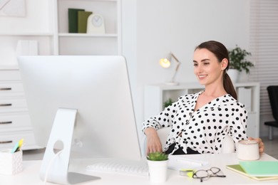 Photo of Smiling businesswoman drinking coffee at table in office. Break time