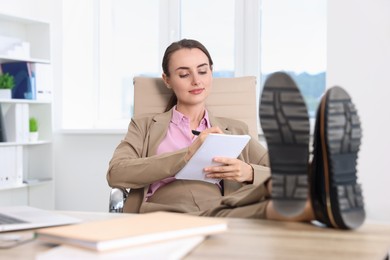 Beautiful businesswoman working and holding legs at table in office