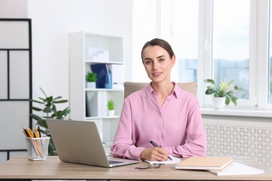 Portrait of smiling businesswoman at table in office