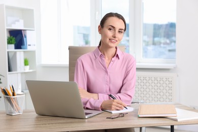 Portrait of smiling businesswoman at table in office