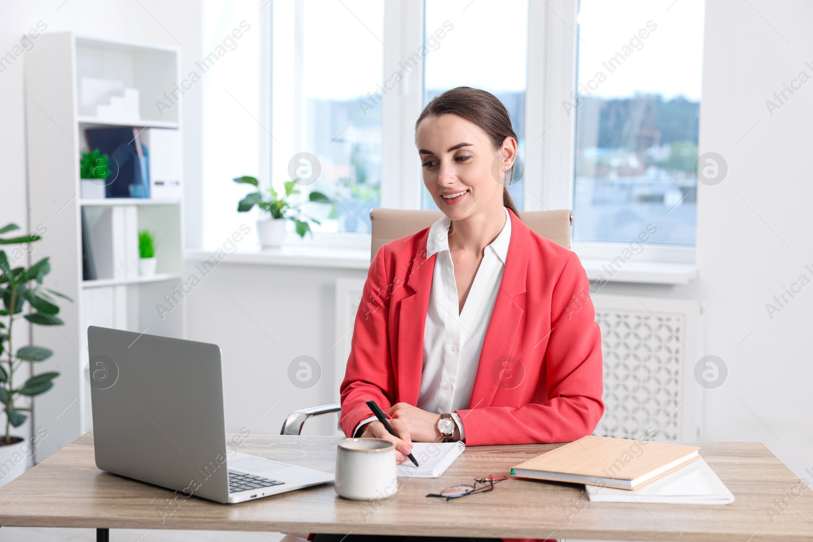 Photo of Smiling businesswoman working at table in office