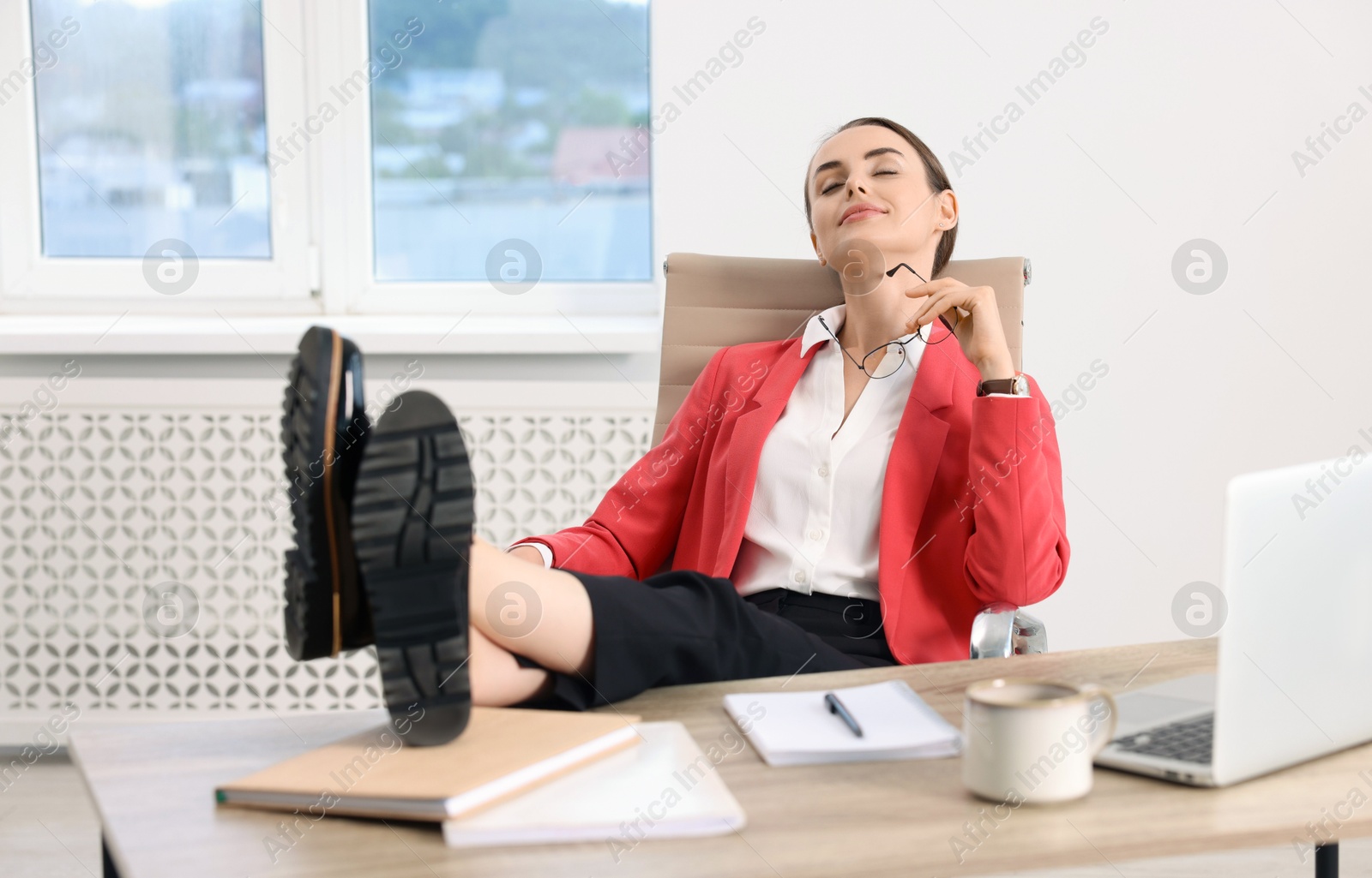 Photo of Beautiful businesswoman holding legs on table in office. Break time