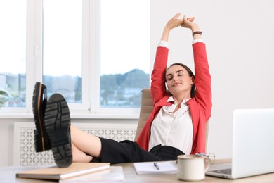 Photo of Beautiful businesswoman holding legs on table in office. Break time