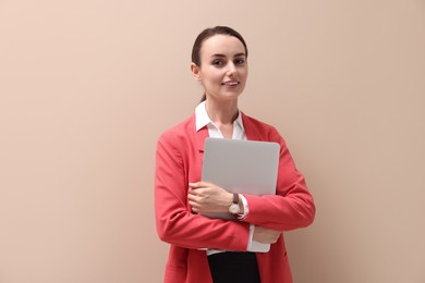 Portrait of smiling businesswoman with laptop on beige background